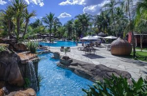 Piscina ao ar livre da Villa do Comendador com espreguiçadeiras e ambiente rodeado por natureza, em uma das pousadas mais charmosas de Pirenópolis.